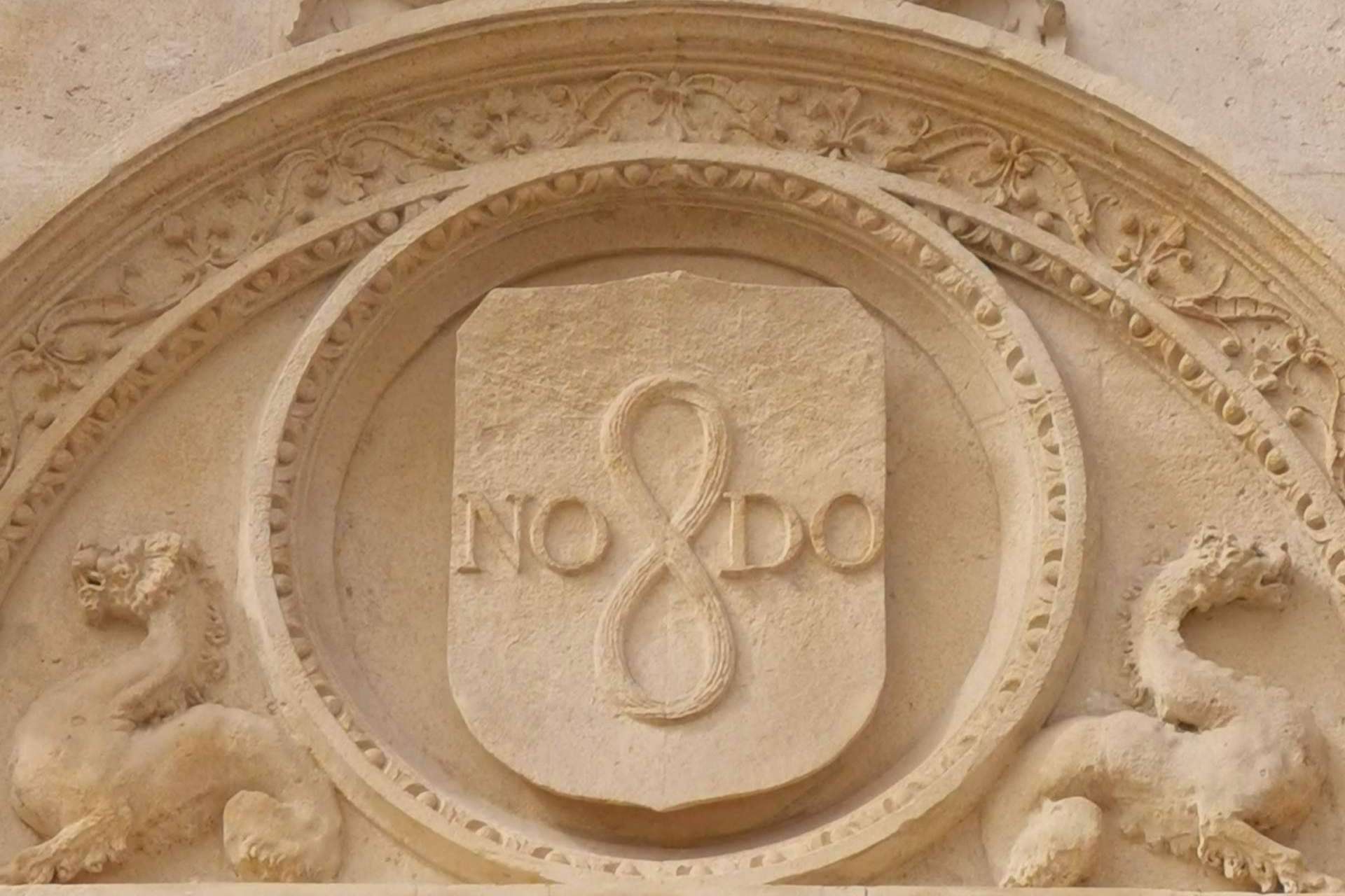 ¿Qué simboliza la inscripción situada en diferentes lugares de Sevilla, NO8DO?